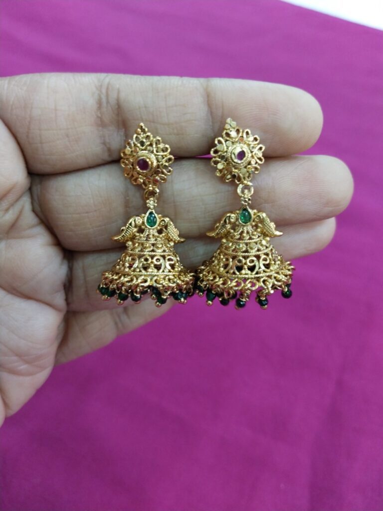 Traditional gold jhumka earrings with filigree design, green bead hangings, and pink stone stud.