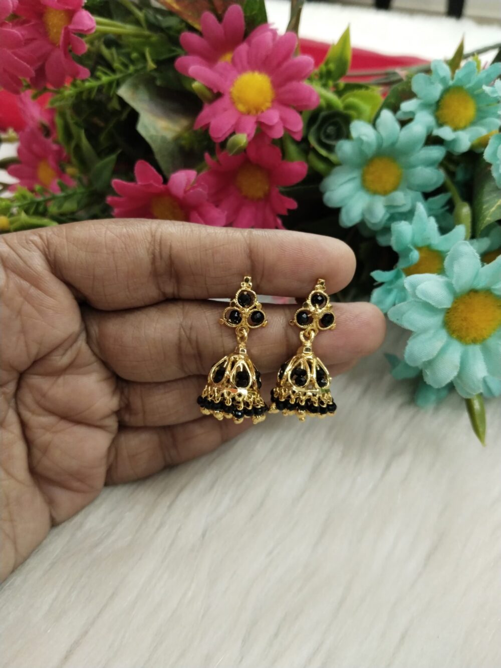 Close-up of woman wearing gold-tone jhumka earring with black beads and traditional Indian design