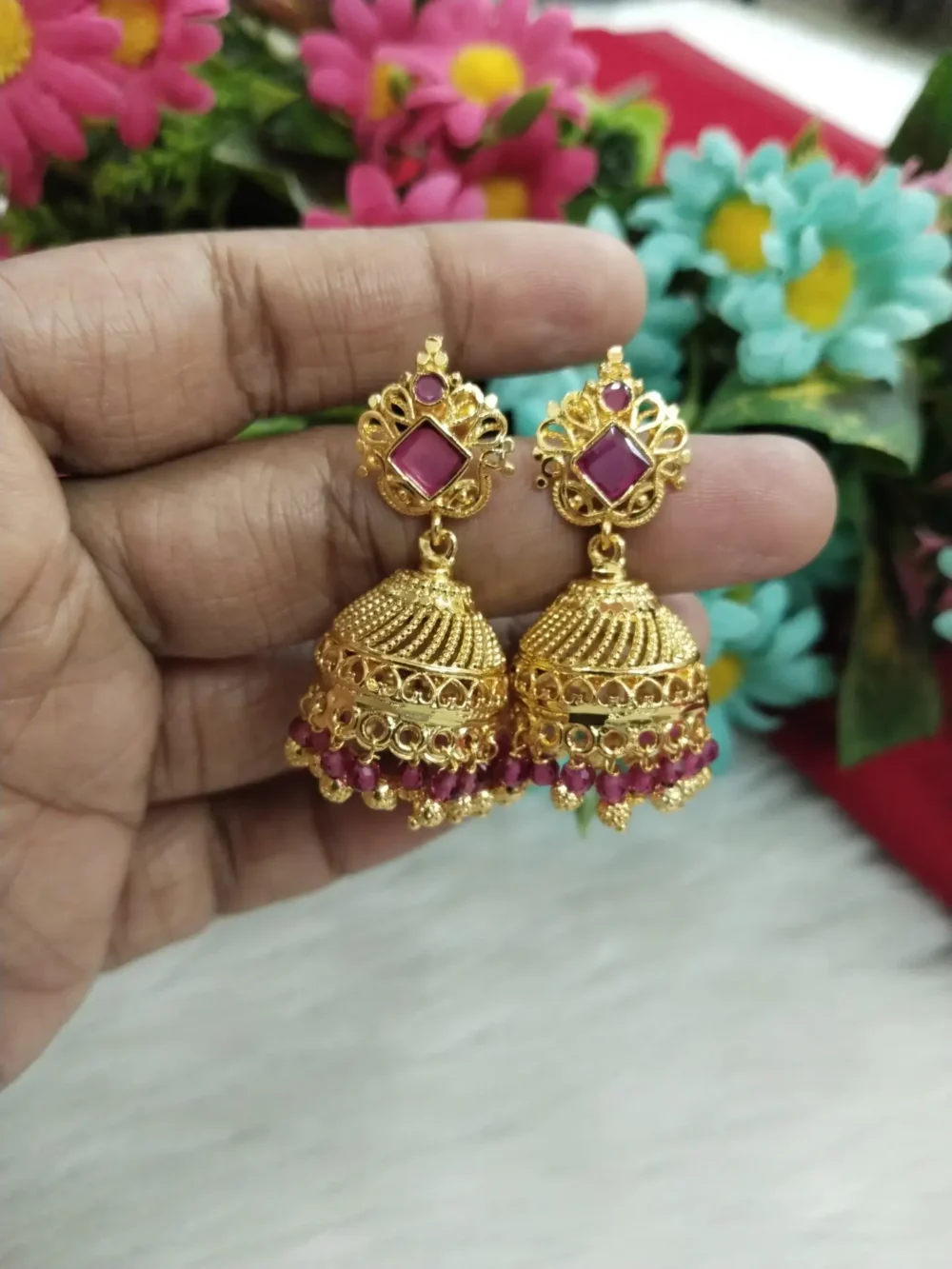 Woman wearing a gold-plated jhumka with pink beads and diamond-shaped stud design