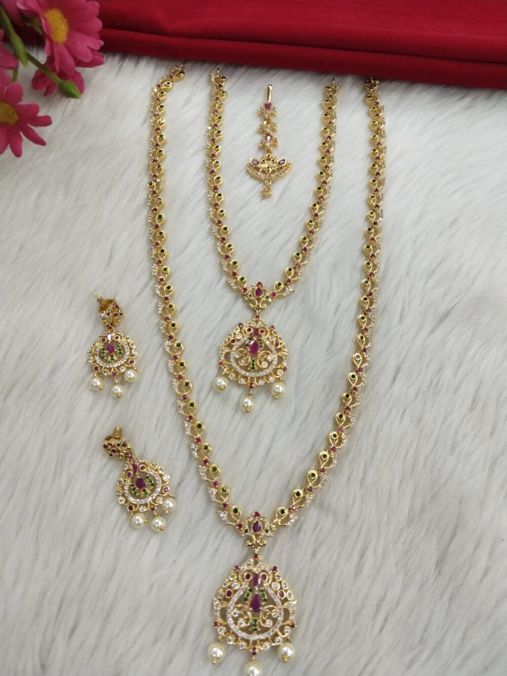 Gold-plated traditional temple jewelry set with ruby, emerald stones and pearl drops on display
